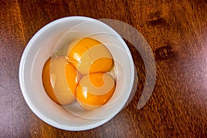 Egg yolks separated in porcelain ramekin on wooden table