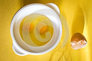 Egg yolks with a whisk on a yellow background