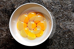 Egg yolks in a white bowl on a stone background