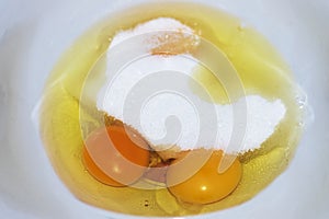 Egg yolks in a white bowl with sugar