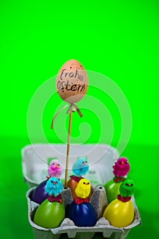 Eggbox with eggs and funny chicks, green background