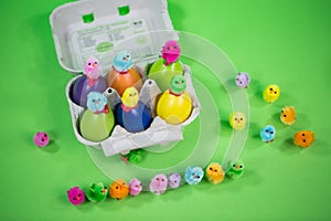 Eggbox with eggs and funny chicks, green background