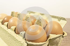 Egge, ten brown eggs in a carton package on a wooden table