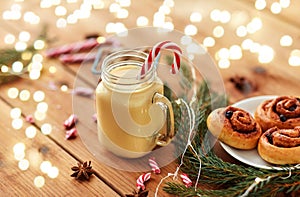 Eggnog with candy cane in mug and cinnamon buns