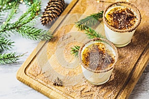 Eggnog with cinnamon and nutmeg for Christmas and winter holidays. Homemade eggnog in glasses on wooden table surface, shallow