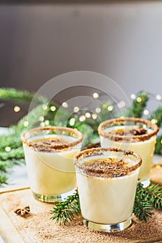 Eggnog with cinnamon and nutmeg for Christmas and winter holidays. Homemade eggnog in glasses on wooden table surface, shallow