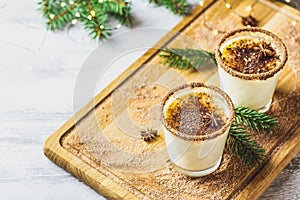 Eggnog with cinnamon and nutmeg for Christmas and winter holidays. Homemade eggnog in glasses on wooden table surface, shallow