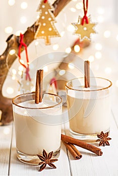 Eggnog in glass cups with a delicate foam, spices and a cinnamon stick