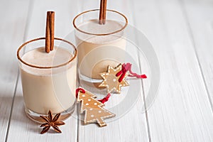 Eggnog in glass cups with a delicate foam, spices and a cinnamon stick