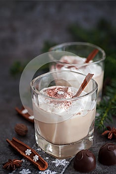 Eggnog in glass cups with a delicate foam, spices and a cinnamon stick