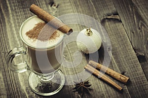 Eggnog in a glass on a wooden background with cinnamoneggnog in