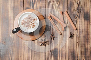 Eggnog. Traditional christmas cocktail in a black mug on a bamboo stand with cinnamon sticks and anise on wooden table. Top view