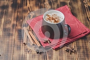 Eggnog. Traditional christmas cocktail in a black mug on a red napkin with cinnamon sticks and anise on wooden table