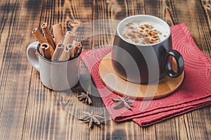 Eggnog. Traditional christmas cocktail in a black mug on a red napkin with cinnamon sticks and anise on wooden table