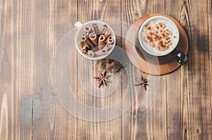 Eggnog. Traditional christmas cocktail in a black mug and white cup with cinnamon sticks and anise on wooden table. Top view and