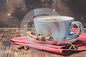 Eggnog. Traditional christmas cocktail in a blue mug with cinnamon sticks and anise on red napkin and wooden table. Background of