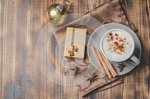 Eggnog. Traditional christmas cocktail, cinnamon sticks on a napkin and with decorations gift box and christmas toy. Wooden