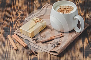 Eggnog. Traditional christmas cocktail, cinnamon sticks on a napkin and with decorations gift box. Wooden table