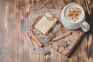 Eggnog. Traditional christmas cocktail, cinnamon sticks on a napkin and with decorations gift box. Wooden table. Top view and