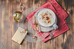 Eggnog. Traditional christmas cocktail, cinnamon sticks on a red napkin and with decorations gift box and christmas toy. Wooden