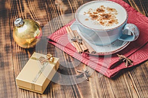 Eggnog. Traditional christmas cocktail, cinnamon sticks on a red napkin and with decorations gift box and christmas toy. Wooden