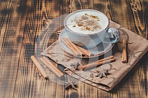 Eggnog. Traditional christmas cocktail in a cup and cinnamon sticks and anise on a napkin.  Wooden background