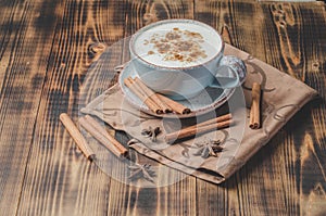 Eggnog. Traditional christmas cocktail in a cup and cinnamon sticks and anise on a napkin.  Wooden background. Copyspace