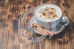 Eggnog. Traditional christmas cocktail in a cup and cinnamon sticks and anise on a wooden background. Copyspace
