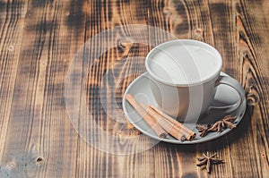 Eggnog. Traditional christmas cocktail in a cup and cinnamon sticks and anise on a wooden background. Copyspace