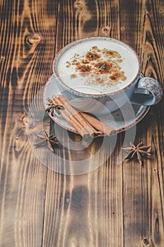Eggnog. Traditional christmas cocktail in a cup and cinnamon sticks and anise on a wooden background. Top view and copyspace