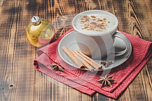 Eggnog. Traditional christmas cocktail in a mug with anise and cinnamon sticks and christmas toy on a wooden table. Background of