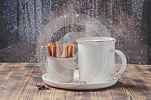 Eggnog. Traditional christmas cocktail in a mug with anise and cinnamon sticks in a small cup on a wooden table. Background of