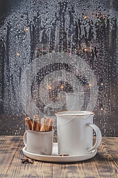 Eggnog. Traditional christmas cocktail in a mug with anise and cinnamon sticks in a small cup on a wooden table. Background of