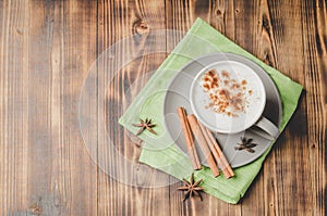 Eggnog. Traditional christmas cocktail in a mug and cinnamon sticks and anise on a green napkin on a wooden background. Top view