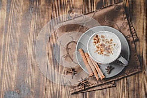 Eggnog. Traditional christmas cocktail in a mug and cinnamon sticks and anise on a napkin on a wooden background. Top view and