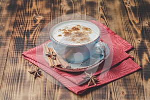 Eggnog. Traditional christmas cocktail in a mug with cinnamon sticks and anise on red napkin and wooden table.