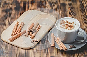 Eggnog. Traditional christmas cocktail in a mug and cinnamon sticks and anise on a white bowl on a wooden background.