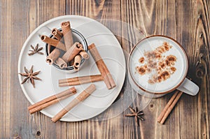 Eggnog. Traditional christmas cocktail in a mug and cinnamon sticks and anise on a white bowl on a wooden background. Top view