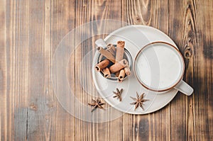 Eggnog. Traditional christmas cocktail in a mug and cinnamon sticks on a on a white bowl on a wooden background. Copyspace and top