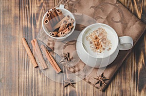 Eggnog. Traditional christmas cocktail in a white mug with cinnamon sticks  and anise on a napkin. Top view. Wooden background