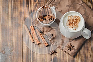 Eggnog. Traditional christmas cocktail in a white mug with cinnamon sticks  and anise on a napkin. Top view. Wooden background.