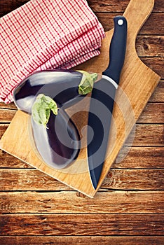 Eggplant or Aubergine with knife on wooden chop board