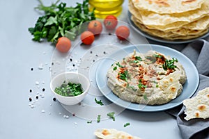 Eggplant dip baba ganoush mutabbal with herbs and paprika on gray wooden background. Selective focus. Traditional arabian food