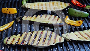 Eggplant grill with vegetables on a cast iron barbecue, sprinkle with spices. Slow motion