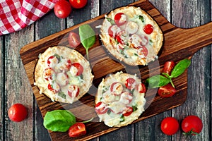 Eggplant mini pizzas on serving board against rustic wood