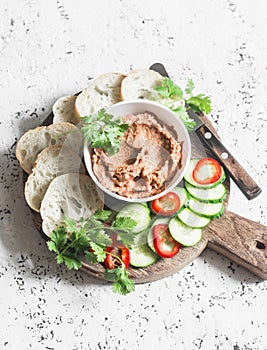 Eggplant, smoked paprika, walnuts dip, vegetables and bread on wooden cutting board on a light background