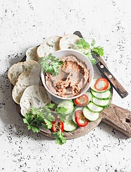 Eggplant, smoked paprika, walnuts dip, vegetables and bread on wooden cutting board on a light background photo