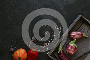 Eggplant varieties in black bowl over dark slate background. Overhead view.