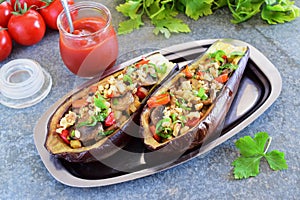 Eggplants stuffed with mushrooms, onions, carrots, tomatoes and nuts on a metal plate on a grey background. Vegetarian food. healt