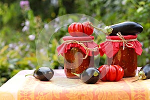 Eggplants in tomatoes in jars are located on a table in the garden.